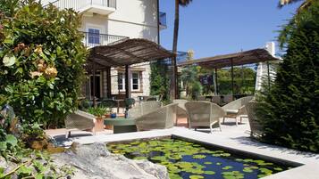 A pool with lily pads, outdoor seating, and a building with a balcony.