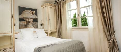 Une chambre à coucher avec un lit, une armoire, une fenêtre avec des rideaux et un tableau au mur.