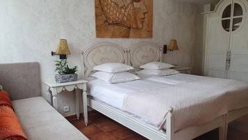 A neatly arranged bedroom with a bed, bedside tables, a lamp, a wardrobe, and a painting on the wall.