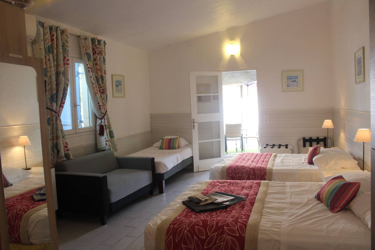 A hotel room with two single beds, a sofa, a chair, and a small table.