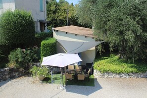 An outdoor patio with a table and chairs, a large umbrella, and a stone wall. - Hotel des Cayrons (Vence)