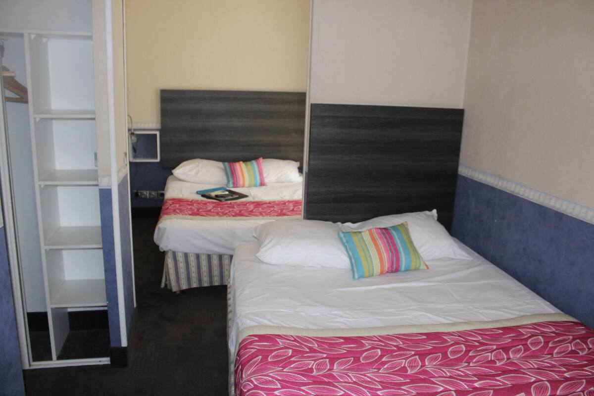 A hotel room with two beds, each with a different patterned bedspread.