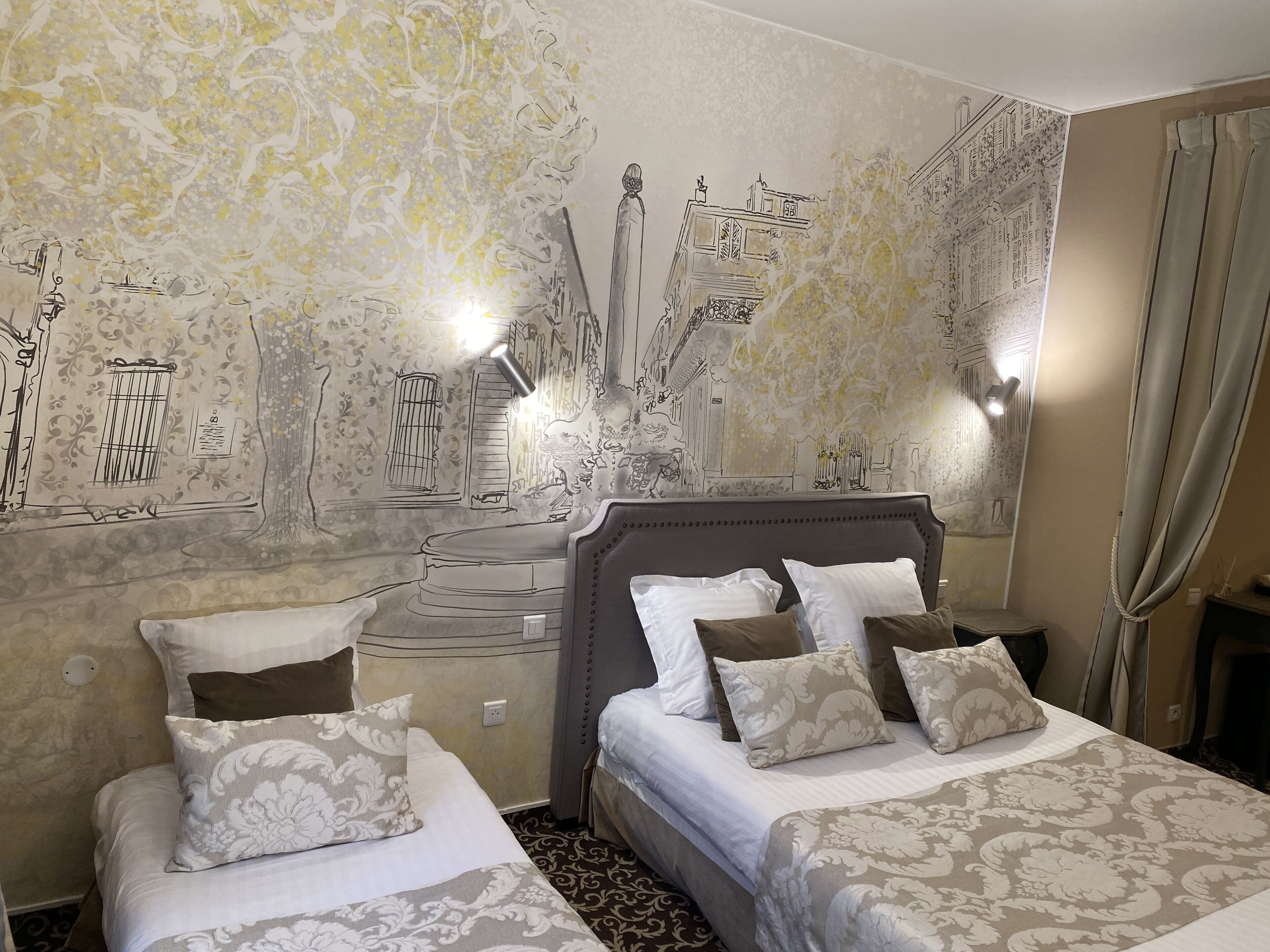 Ein Hotelzimmer mit zwei Betten, einer großen Wandmalerei und einer Kristallleuchtre.