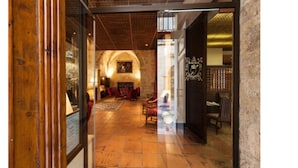 An interior view of a hotel lobby with a wooden floor, a stone wall, and a chandelier. - Hotel des Augustins (Aix-en-Provence)
