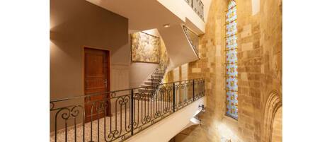 Un magnifique escalier avec une rampe en fer forgé, une porte en bois et un vitrail.