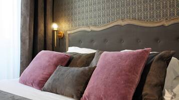 A neatly made bed with a tufted headboard, a patterned wall, and a wall-mounted light fixture.