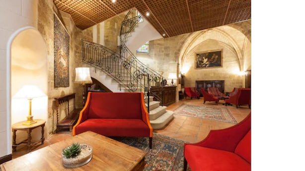 A lobby with a staircase, red armchairs, a wooden coffee table, and a lamp. - Hotel des Augustins (Aix-en-Provence)