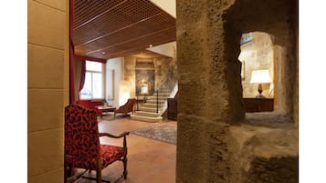 A lobby with a red patterned chair, a staircase, and a stone wall.