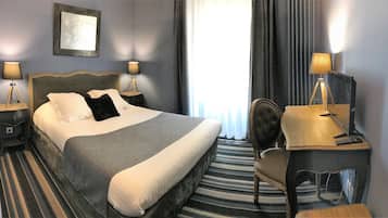 Una camera d'albergo con un letto grande, due lampade ai comodini, una scrivania con un computer e una sedia.