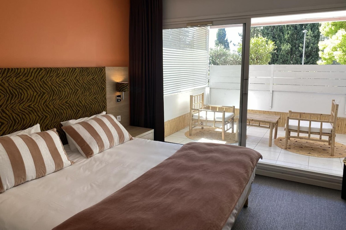 Une chambre d’hôtel avec un lit, une table de chevet, une lampe et une vue sur la terrasse extérieure.