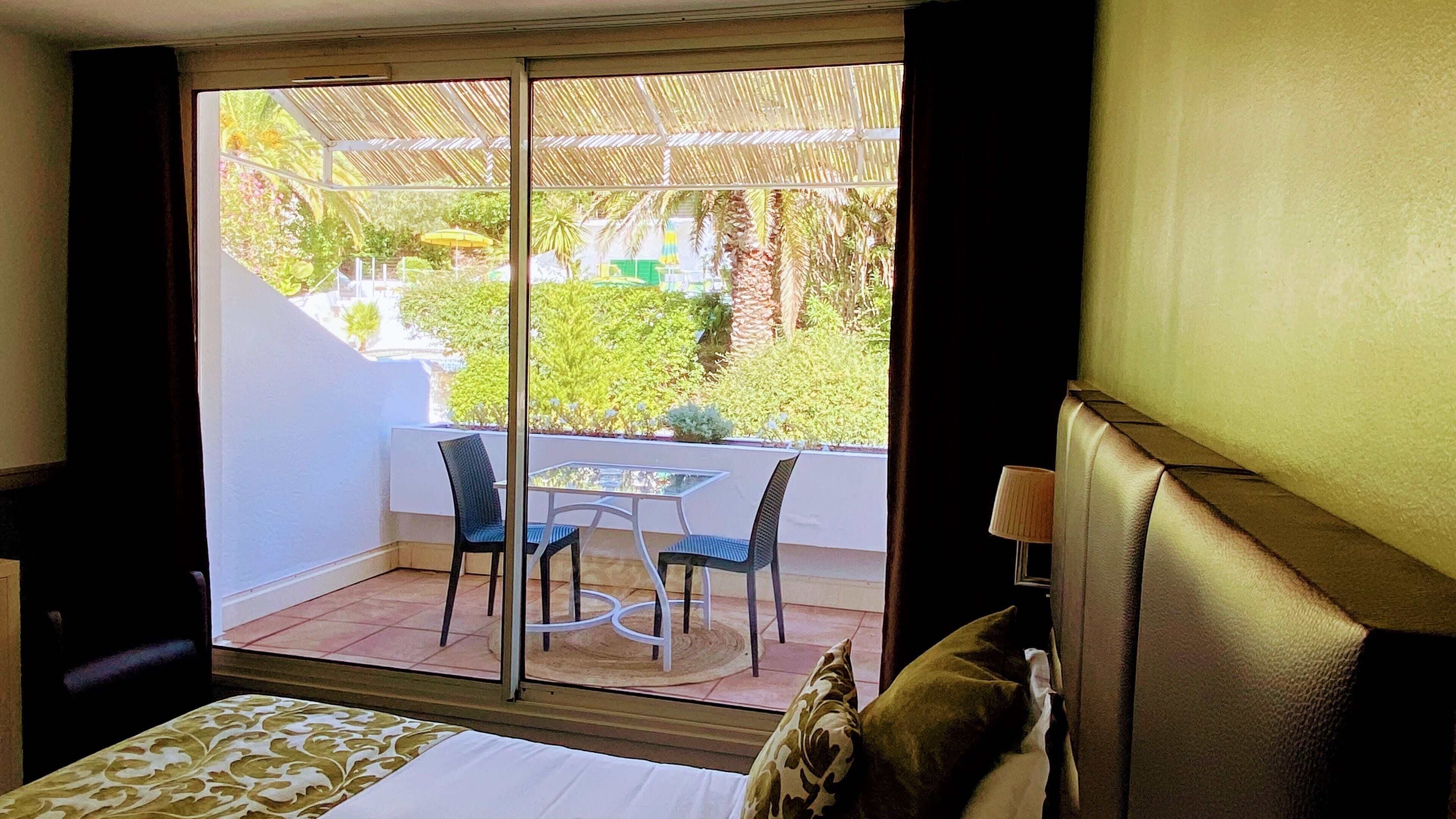 Una stanza con un letto, un tavolino con due sedie e vista su un balcone con tavolo e sedie.