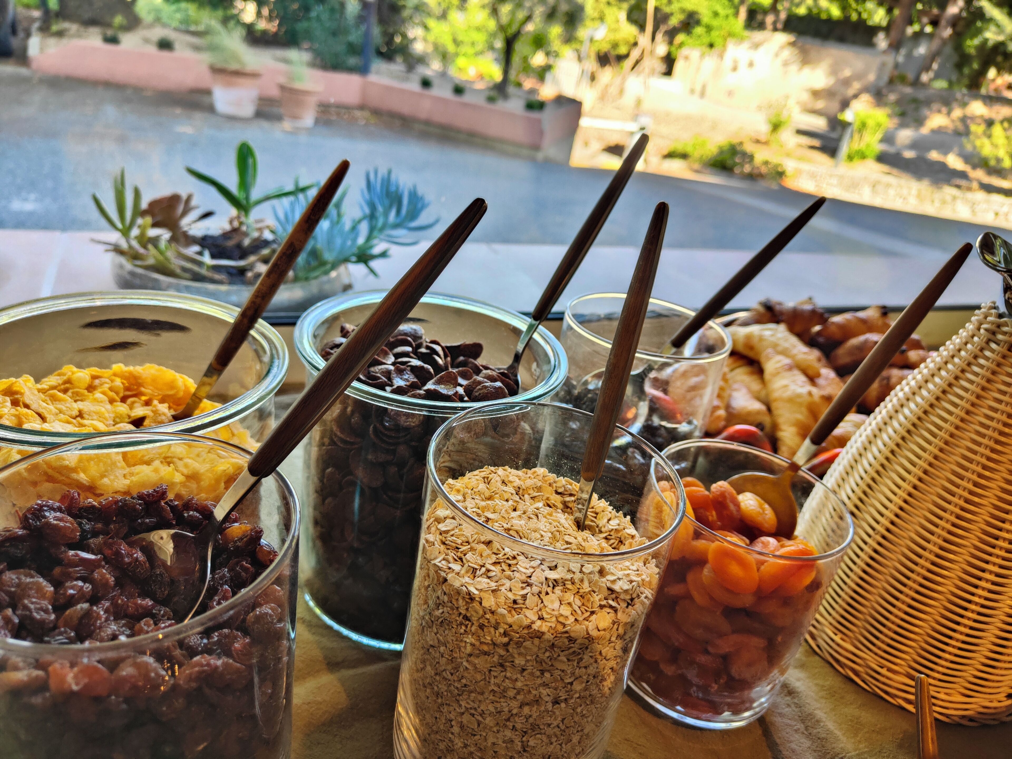 A table with various food items in glass containers, including dried fruits, nuts, and granola.