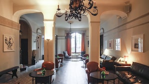 En hotellobby med en lysekrone, lædersofaer og en pejs.