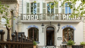 En historisk bygning med skiltet "NORD HOTEL" og "NORD PINTS" som angiver en restaurant. Der er udendørs siddeområder med borde og stole.
