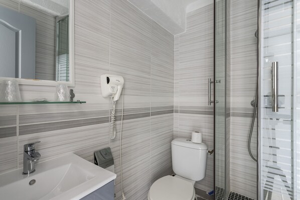 Une salle de bain moderne avec une douche à parois de verre, des toilettes et un lavabo avec un miroir au-dessus.