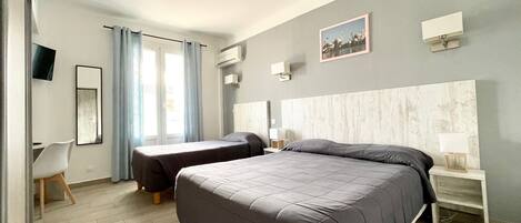 A modern hotel room with two beds, a desk, and a chair.