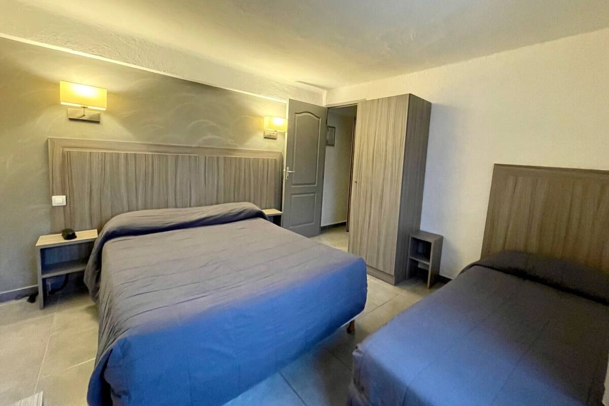 Ein Hotelzimmer mit zwei Betten, einem Kleiderschrank und einem Nachttisch mit Lampe.