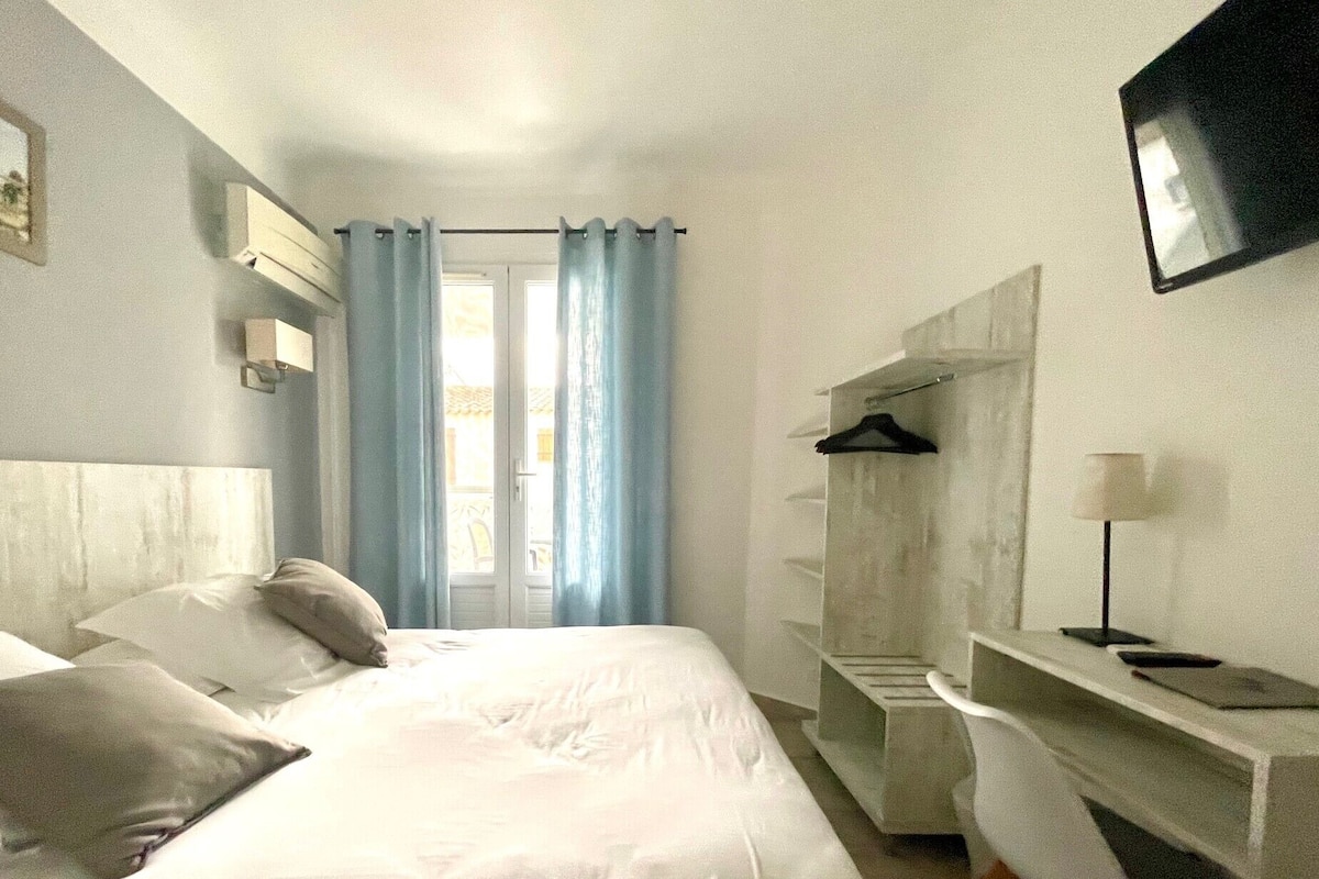 Ein Hotelzimmer mit einem Bett, einem Schreibtisch mit Stuhl, einem an der Wand befestigten Fernseher und einem Kleiderschrank.