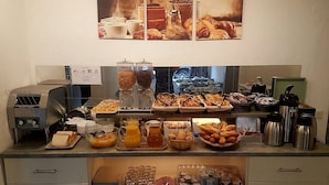 Un bufé de desayuno con diferentes alimentos, una cafetera y un tostador.
