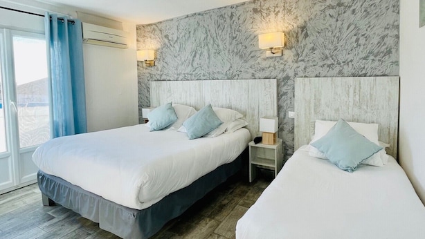 Habitación de hotel con dos camas, paredes con diseño de mármol y vistas al exterior.