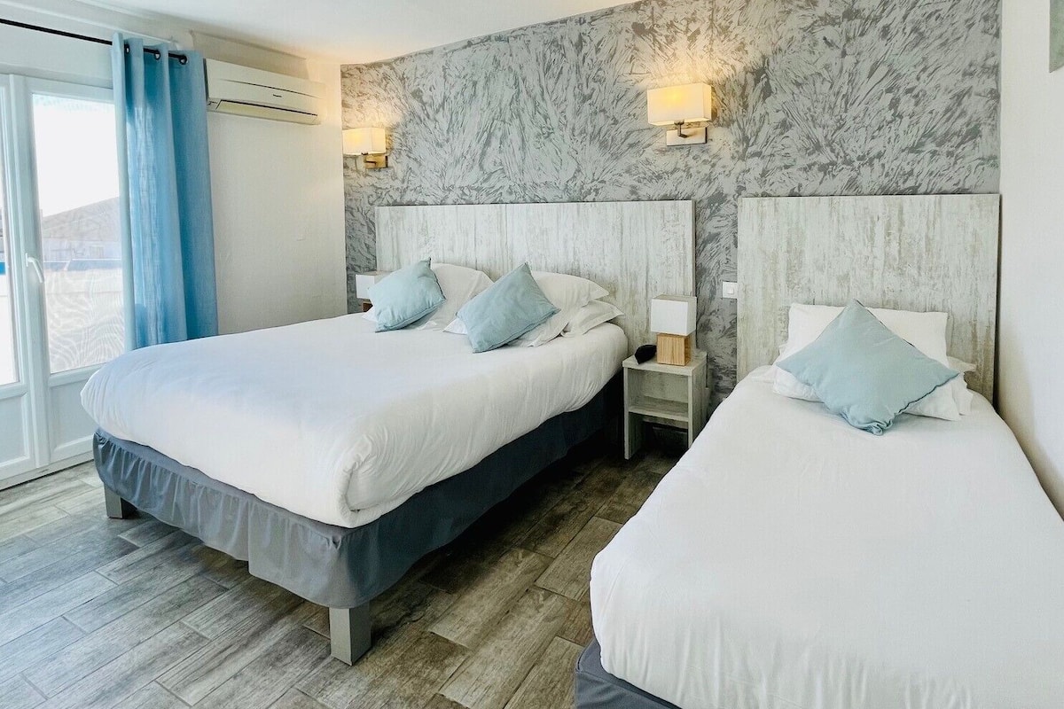 Ein Hotelzimmer mit zwei Betten, Wänden mit Marmormuster und Blick ins Freie.
