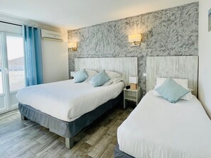Une chambre d’hôtel avec deux lits, des murs décorés d’un motif imitant le marbre et une vue sur l’extérieur.