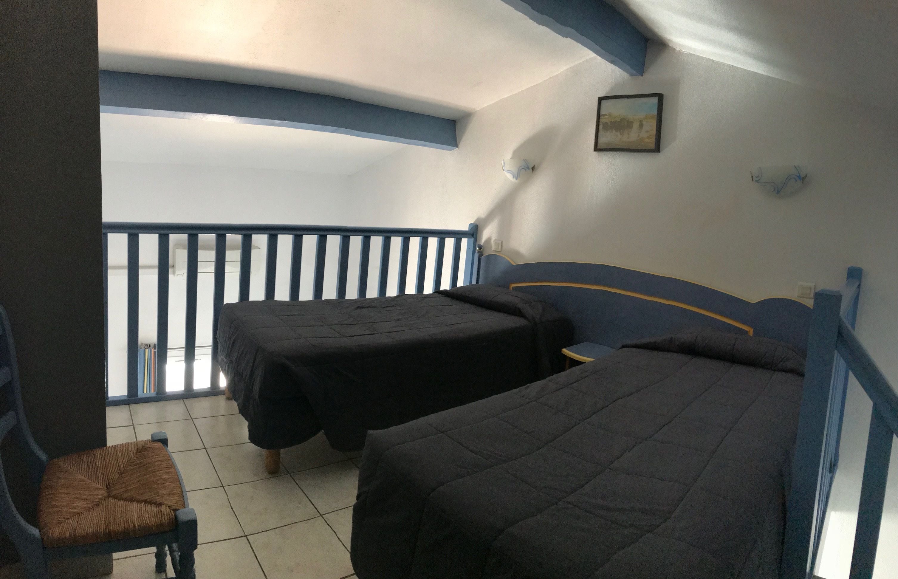 Una habitación con dos camas, una silla y una mesita.