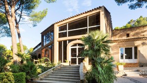 A two-story building with a stone staircase leading to the entrance, surrounded by lush greenery and trees. - Best Western Domaine de Roquerousse (Salon-de-Provence)