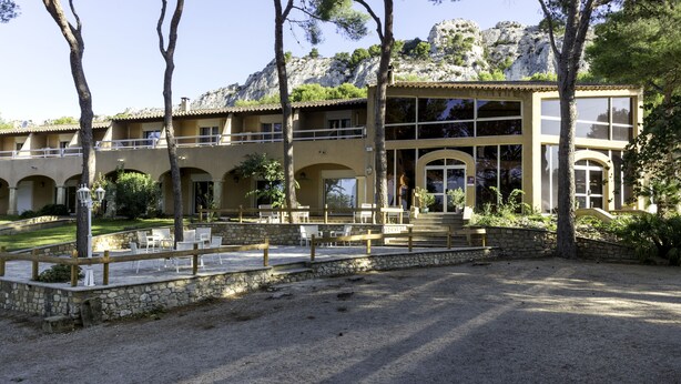 A two-story building with a courtyard, outdoor seating, and a view of rocky hills. - Best Western Domaine de Roquerousse (Salon-de-Provence)