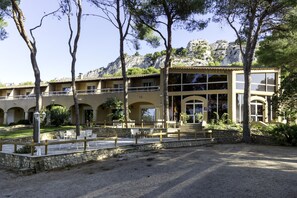 A two-story building with a courtyard, outdoor seating, and a view of rocky hills. - Best Western Domaine de Roquerousse (Salon-de-Provence)