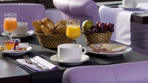A breakfast table with a view of a green landscape, including trees and a body of water. - Hôtel Ariane (Fos-sur-Mer)