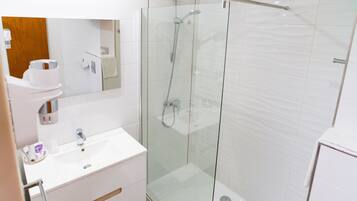 A modern bathroom with a glass-enclosed shower, a white sink, and a mirror above the vanity.
