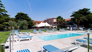 A pool area with lounge chairs, a swimming pool, and a building labeled "Ariane Hotel" in the background. - Hôtel Ariane (Fos-sur-Mer)