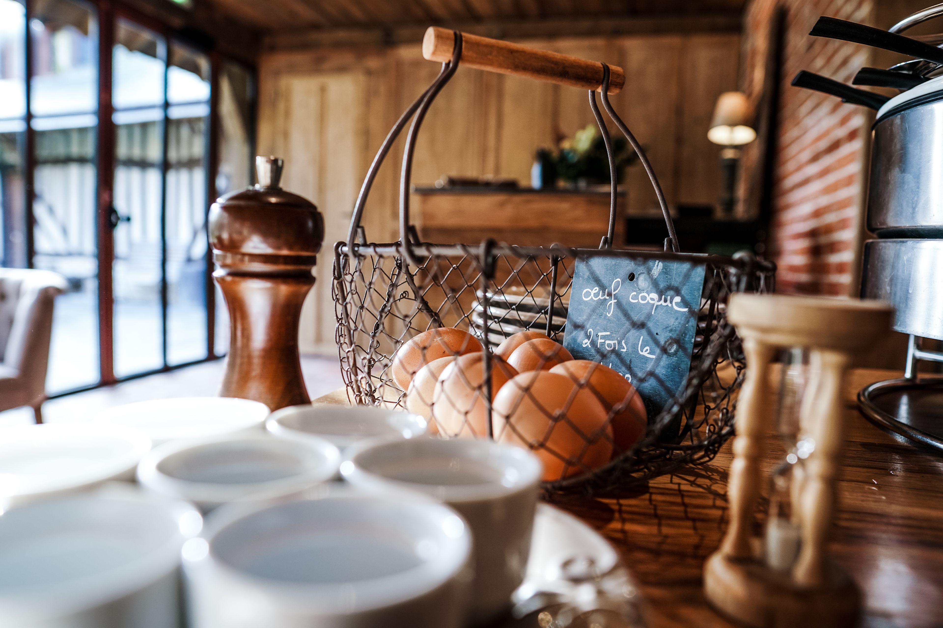 Una cesta de huevos sobre una mesa con un cartel de pizarra que dice 'café' y 'a la forchetta'.