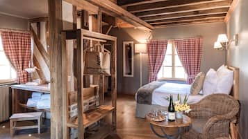 A rustic room with a wooden desk, a bed with checkered curtains, and wicker furniture.