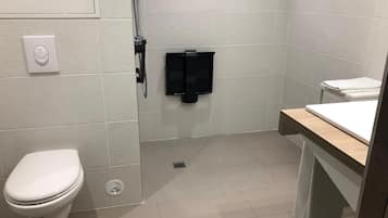 Uma casa de banho moderna com sanita, chuveiro e lavatório.