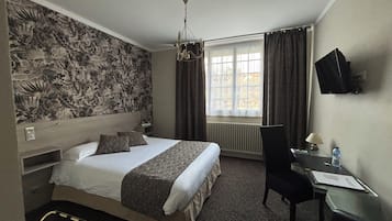 Una habitación de hotel con una cama grande, un escritorio, una silla, un televisor y una ventana con cortinas.