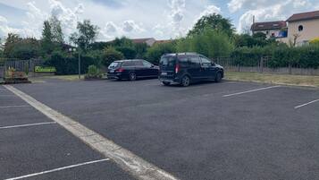 Un estacionamiento con dos coches y un cartel de recepción al fondo.