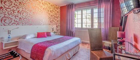 Habitación de hotel con cama, una silla, una mesa y ventana con cortinas.