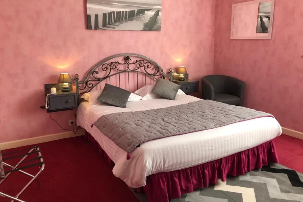 A bedroom with a bed, two bedside tables with lamps, a chair, and artwork on the walls.
