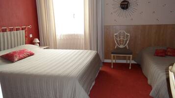 Una habitación de hotel con una cama grande, una silla y dos camas más pequeñas.