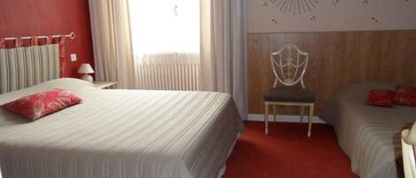 Una habitación de hotel con una cama grande, una silla y dos camas más pequeñas.