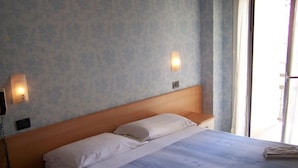 Une chambre d’hôtel avec un lit, des tables de chevet, un téléphone fixé au mur et une fenêtre avec des rideaux.