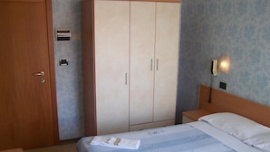 Une chambre d’hôtel comprenant un lit, une armoire, une table de chevet et un téléphone.