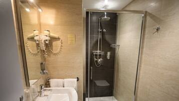 Un baño moderno con ducha de vidrio, lavamanos y espejo.