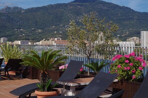 A rooftop terrace with lounge chairs, potted plants, and a view of a mountainous landscape. - Spunta Di Mare (Ajaccio)