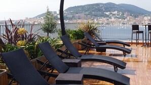 A rooftop terrace with lounge chairs, a wooden deck, and a cityscape view. - Spunta Di Mare (Ajaccio)