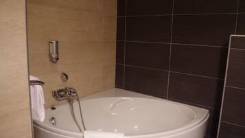 Un baño moderno con una bañera independiente, un cabezal de ducha manual y un perchero para toallas.