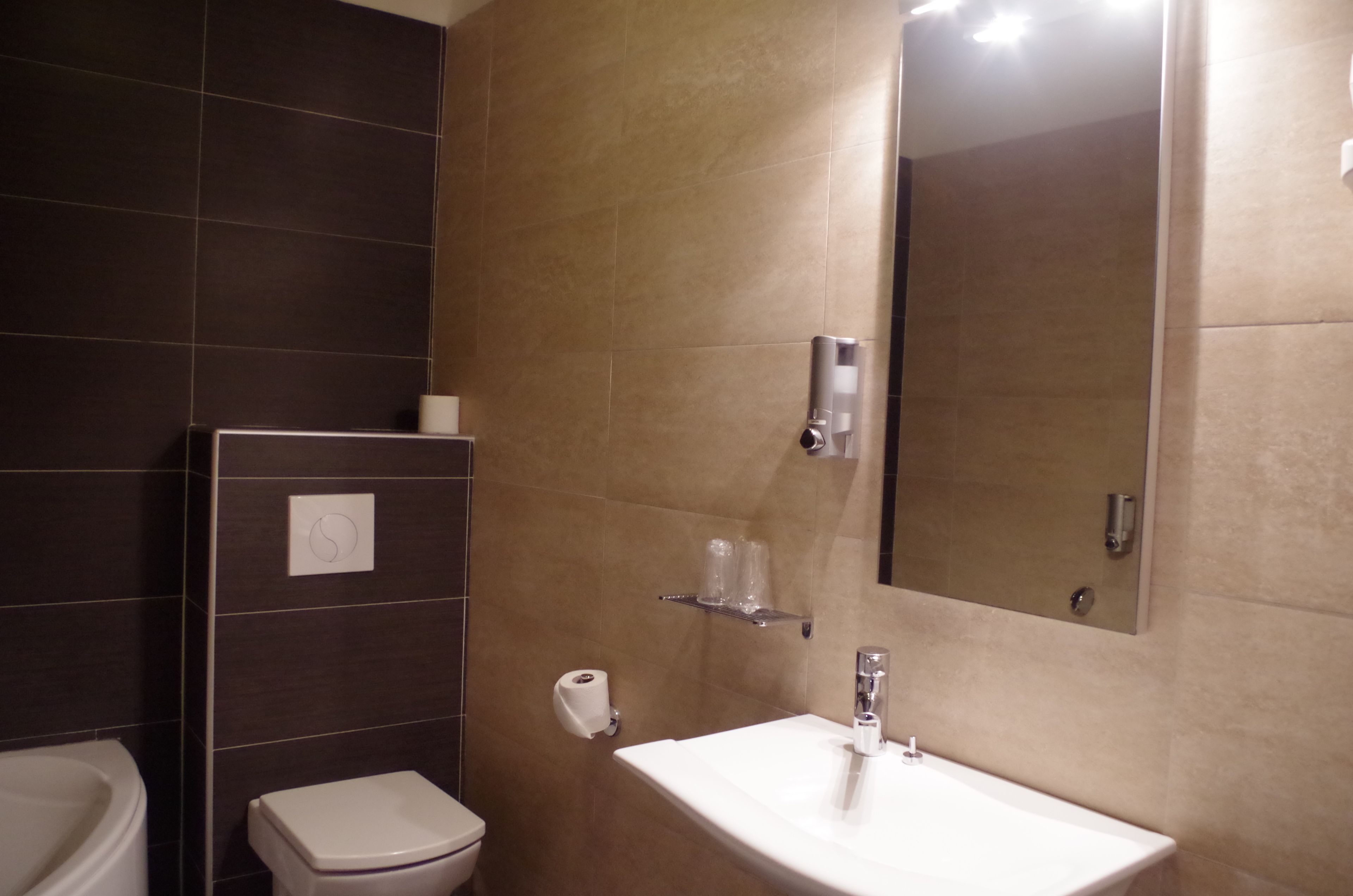 Un baño con inodoro, lavamanos, espejo y perchero para toallas.