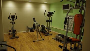 Une salle de sport équipée de divers appareils d’exercice, notamment des tapis de course, des vélos d’appartement et des appareils de musculation.